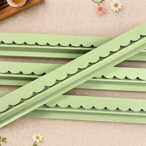 May include: Four long, light green plastic strips featuring a decorative scalloped edge along one side. These rigid, straight components have a uniform matte finish and a consistent profile, designed with a flat base and a raised, curved border.