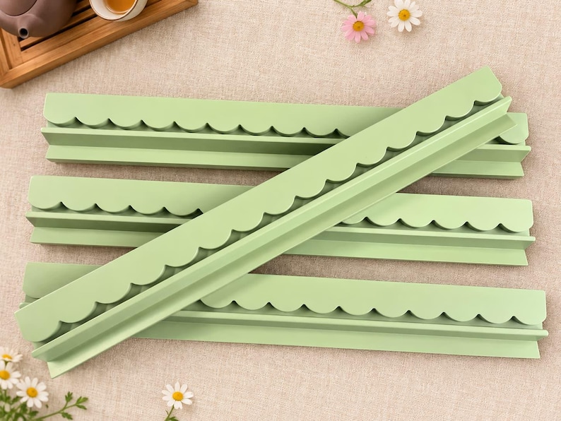May include: Four long, light green plastic strips featuring a decorative scalloped edge along one side. These rigid, straight components have a uniform matte finish and a consistent profile, designed with a flat base and a raised, curved border.