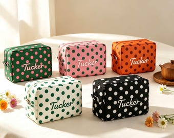May include: Five rectangular toiletry bags featuring a polka dot pattern and the name Tucker embroidered on the front. The bags come in green with pink dots, pink with green dots, orange with brown dots, white with green dots, and black with white dots.