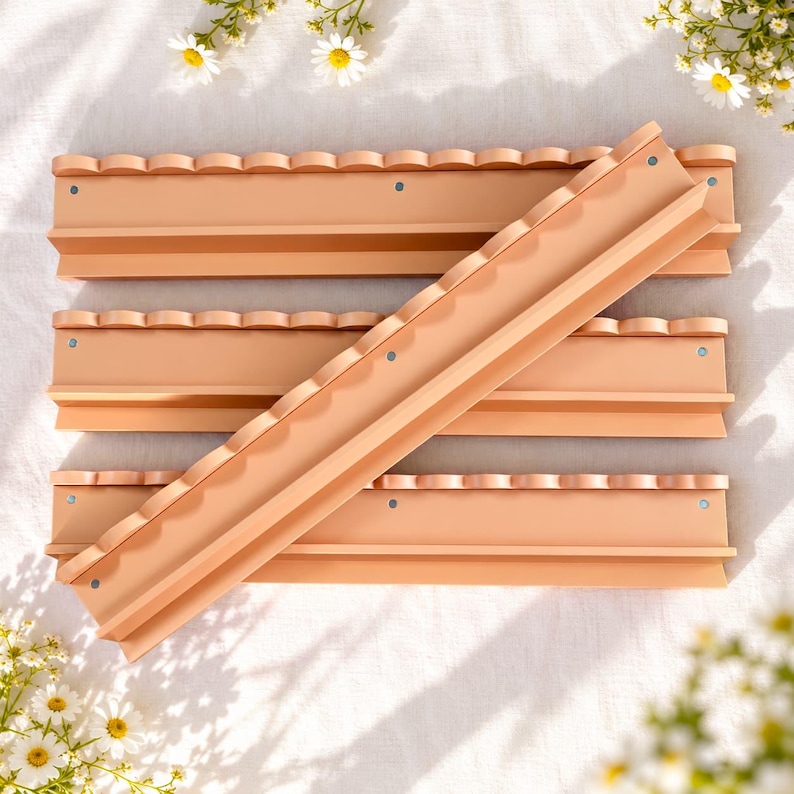 May include: Four peach-colored wall-mounted shelves arranged in a stack. Each shelf features a scalloped top edge and a flat horizontal surface with small circular screw holes visible along the front face of the shelf structure.