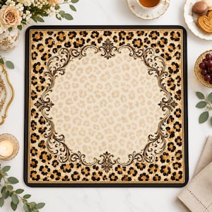 Op de afbeelding: Een vierkante placemat met een centraal crèmekleurig gedeelte met een subtiel luipaardpatroon, omringd door een donkerbruine rand met een opvallende luipaardprint en een sierlijk, symmetrisch zwart filigraankader in het midden.