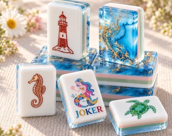 May include: A collection of rectangular mahjong tiles featuring white faces with colorful illustrations of a red lighthouse, a brown seahorse, a mermaid with the text JOKER, and a green sea turtle, alongside tiles with blue and gold marble patterns.