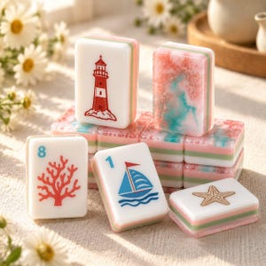 May include: A collection of rectangular mahjong tiles featuring nautical designs including a red lighthouse, a blue sailboat, a red coral branch, and a gold starfish. Some tiles have a pink and teal marbled pattern, with layered white, green, and pink sides.