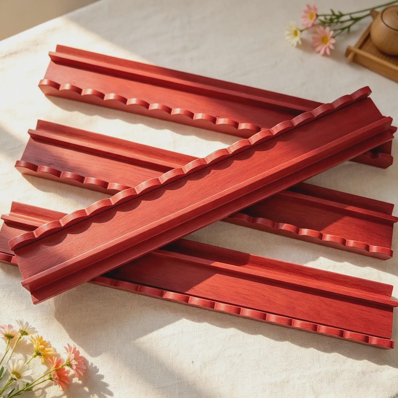 May include: A set of four long, rectangular wooden racks stained in a deep reddish-brown hue. Each rack features a raised back edge and a front edge with a series of uniform, scalloped semi-circular cutouts designed to hold items securely in place.