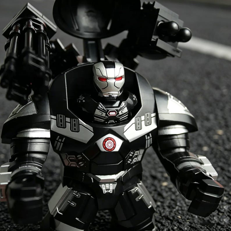 Puede incluir: Figura de acci&oacute;n de War Machine negra y plateada con ojos rojos. La figura tiene un dise&ntilde;o detallado con m&uacute;ltiples armas unidas a la espalda y los hombros. La figura est&aacute; de pie sobre una superficie oscura.