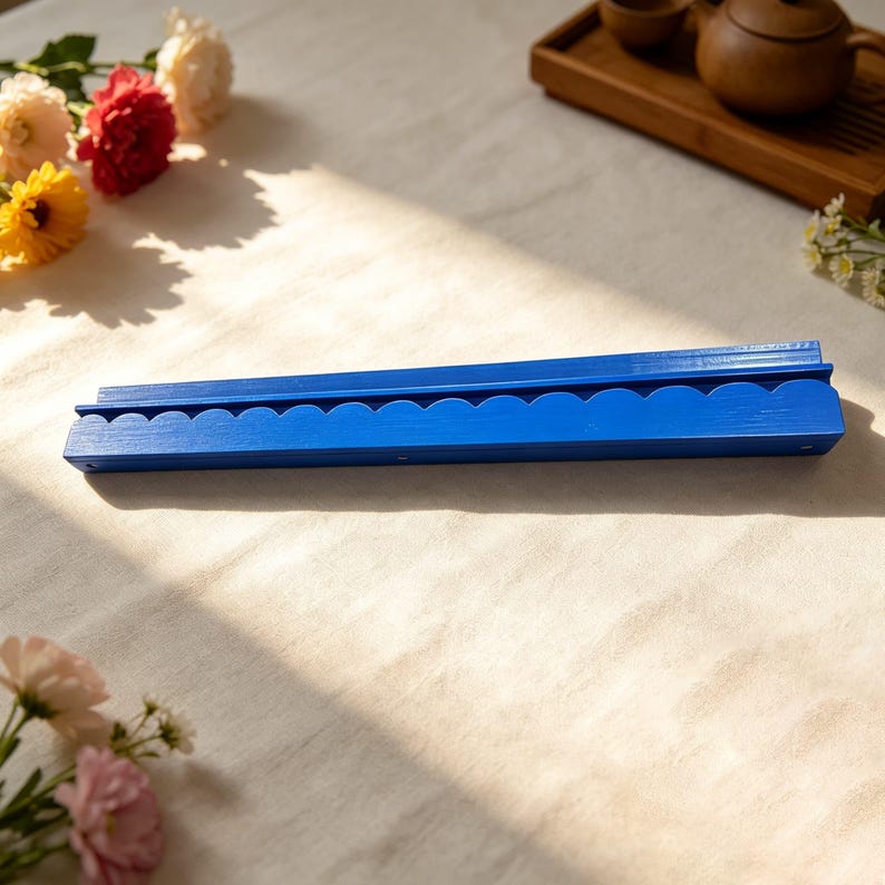 May include: A long, rectangular blue wooden wall shelf featuring a decorative scalloped edge along the front. The shelf has a flat top surface and a grooved design, finished in a solid, vibrant blue paint with a visible wood grain texture.