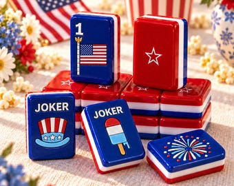 May include: A set of rectangular game tiles featuring red, white, and blue designs. The tiles display patriotic imagery including the American flag, a star, a top hat, a popsicle, and fireworks, with some tiles labeled with the word JOKER.
