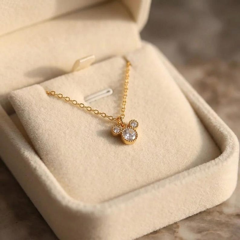 Auralis signature jewelry box presenting a dainty 18K gold plated crystal necklace, designed to be stored away from moisture and chemicals.