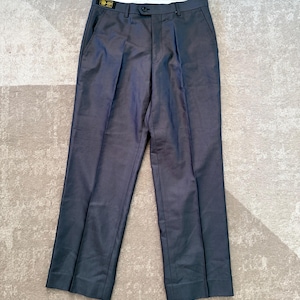May include: Dark gray dress pants with a button closure and pleats. The pants have two front pockets and two back pockets. A small tag is visible on the waistband. The pants are laid flat on a light-colored surface.