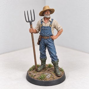May include: A detailed figurine of a bearded farmer wearing a straw hat, a light-colored shirt, and blue denim overalls with a brown belt. The figure holds a tall wooden pitchfork and stands on a circular base decorated with small plants and dirt.