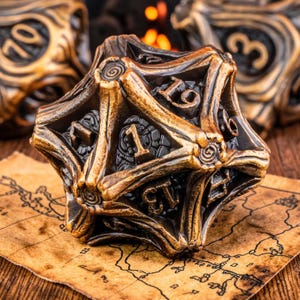 May include: Bronze-colored, multi-sided die with numbers, resting on a map. The die has a detailed, textured surface with raised numbers. Other dice are visible in the background, suggesting a set. The overall theme is gaming.