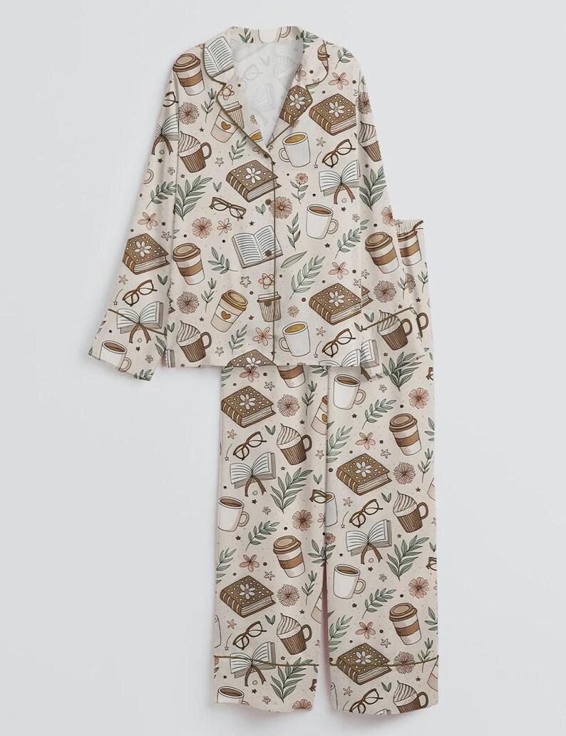 May include: A beige pajama set featuring a repeating pattern of books, coffee cups, eyeglasses, and flowers. The long-sleeved top has a button-down front and a notched collar. The pants are straight-legged.