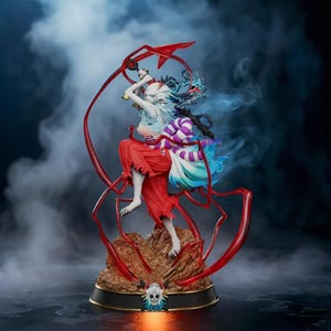 May include: A detailed figurine of a character in a dynamic pose, wielding a sword with a red blade. The figure has white and blue hair, red clothing, and stands on a rocky base. The base has a skull emblem and is surrounded by red accents.