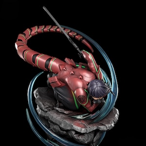 Può includere: Statuetta dettagliata di un personaggio in armatura rossa e nera con coda di scorpione, che tiene una spada. La figura è posata su una base rocciosa con accenti blu, su sfondo nero.