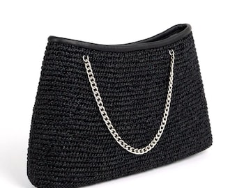 Bolsa de ombro preta em crochê com detalhes em pele de cordeiro e alça de corrente prateada.