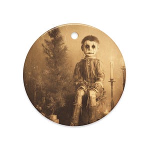 May include: A sepia-toned, round Christmas ornament featuring a vintage illustration of a doll with dark eye makeup and a sad expression. The doll is seated near a small Christmas tree and lit candles, creating a spooky holiday theme.