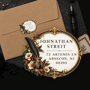 Könnte beinhalten: Ein ovales Adressetikett mit einer Illustration eines schwarzen Tintenfasses und einer Feder, umgeben von weißen Blüten und roten Beeren. Der Text lautet: JOHNATHAN STREIT, 72 ARTEMIS LN, ABSECON, NJ 08205. Das Etikett hat einen verzierten Gold-Schwarz-Rahmen.