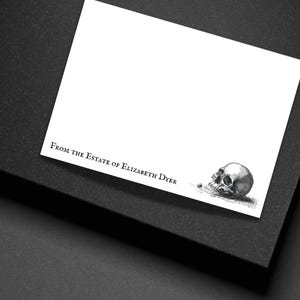 May include: A white card with the text "From the Estate of Elizabeth Dyer" and a detailed illustration of a human skull. The card is set on a dark surface, creating a contrast.
