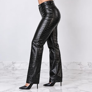 May include: Black high-waisted trousers featuring a glossy, embossed crocodile skin texture. These full-length trousers have a straight-leg cut, a button and zip fly closure, and visible belt loops, paired with black pointed-toe high-heeled pumps.