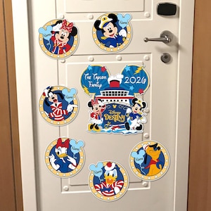 Könnte beinhalten: Eine Sammlung von Disney-Magneten mit Mickey Mouse, Minnie Mouse, Donald Duck, Daisy Duck, Goofy und Pluto. Die Magnete haben ein blau-gelbes kreisförmiges Design mit einem Herzrand. Einige Magnete haben ein Namensschild. Ein größerer Magnet zeigt den Text "Disney Destiny" und "The Taylor Family 2026".