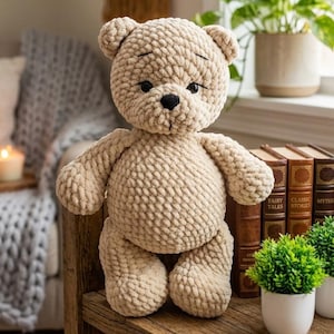 May include: A beige crocheted teddy bear with a textured surface. The bear has a black nose and eyes, and is standing on a wooden surface. The bear is a soft toy.