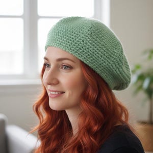May include: A light green, knitted beret. The beret is made of a soft, textured yarn and has a classic, round shape. The hat is a solid color and appears to be handmade. The beret is a stylish accessory.