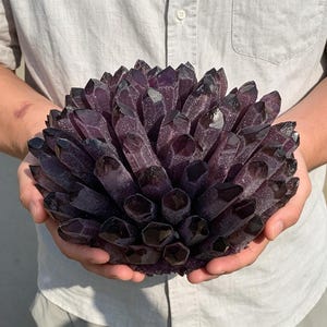 May include: A large, spherical cluster of deep purple amethyst crystals. The specimen features numerous pointed, translucent crystal points radiating outward from a central base, displaying a dark, saturated violet hue throughout the structure.