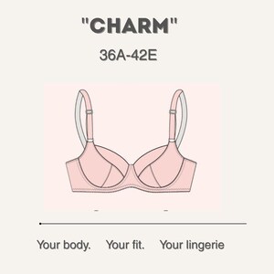 Puede incluir: Un sujetador rosa claro con tirantes ajustables y aros. El sujetador se muestra sobre un fondo rosa claro. El texto encima del sujetador dice "CHARM" y "36A-42E". Debajo del sujetador, el texto dice "Your body. Your fit. Your lingerie."