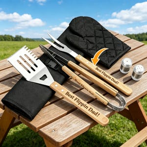 Peut inclure: Un ensemble de barbecue avec des outils en acier inoxydable et des manches en bois, comprenant une spatule, des pinces et une fourchette. Les manches sont gravés de "Best Flippin Dad!" et l'ensemble comprend un gant de cuisine noir et des salières et poivrières.