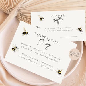 Könnte beinhalten: Zwei cremefarbene Babyparty-Einladungskarten mit Bienenillustrationen. Auf einer Karte steht "Diaper Raffle" und auf der anderen "Books for Baby". Die Karten haben schwarzen Schrifttext und Aquarell-Bienengrafiken.