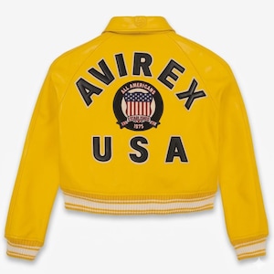 May include: A bright yellow jacket with the word "AVIREX" arched across the back in black lettering. Below the brand name is a circular emblem with the words "ALL AMERICANS" and "ESTABLISHED 1975". The word "USA" is printed below the emblem.