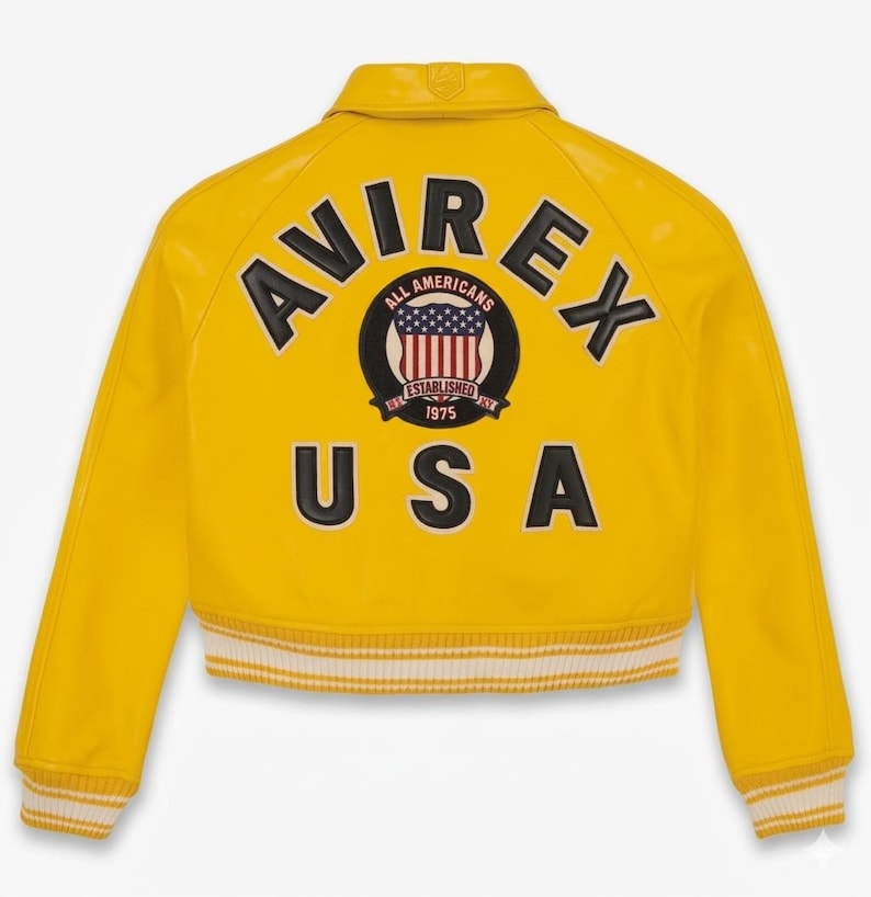 May include: A bright yellow jacket with the word "AVIREX" arched across the back in black lettering. Below the brand name is a circular emblem with the words "ALL AMERICANS" and "ESTABLISHED 1975". The word "USA" is printed below the emblem.