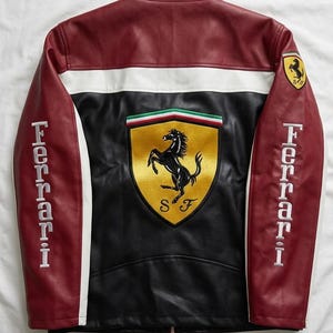 Op de afbeelding: Leren jas met een colorblock-ontwerp met bordeauxrode, witte en zwarte panelen. De jas heeft het Ferrari-logo op de rug en mouwen, met het woord "Ferrari" op de mouwen geborduurd.