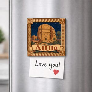 Puede incluir: Un imán de nevera cuadrado con una ilustración de la formación rocosa de AlUla bajo un cielo estrellado, enmarcado por un borde decorativo marrón. Debajo de la imagen, una nota blanca está sujeta con el texto Love you! y un corazón rojo.