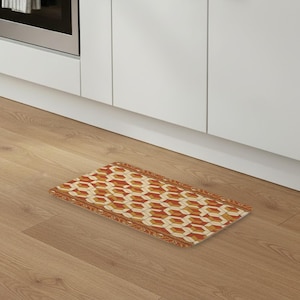 Può includere: Un tappetino rettangolare caratterizzato da un motivo geometrico ripetitivo di cubi arancioni, gialli e bianchi. Il tappetino è bordato da una decorazione floreale in arancione e bianco, che crea una cornice visiva per il design.