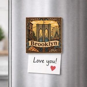 Op de afbeelding: Een vierkante koelkastmagneet met een gedetailleerde illustratie van de Brooklyn Bridge, een reuzenrad en een pizzapunt. Het woord Brooklyn staat op een decoratieve banner. Een wit briefje met de tekst Love you! en een rood hart is bevestigd.