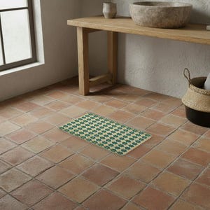 Può includere: Un tappetino rettangolare con un motivo geometrico ripetuto in verde scuro, crema e oro. Il tappetino presenta un design strutturato simile a piastrelle, con piccoli motivi a stella a quattro punte al centro di ogni segmento.