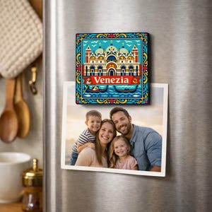 May include: A colorful square magnet featuring a Venice, Italy, design with the word "Venezia" and gondolas. The magnet is displayed on a refrigerator next to a family photo.