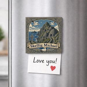 Może przedstawiać: Kwadratowy magnes na lodówkę z ilustracją Skellig Michael przedstawiającą kamienne chaty w kształcie uli, celtycki krzyż i latające głuptaki. Pod obrazkiem znajduje się biała prostokątna karteczka z odręcznym napisem Love you! oraz czerwonym sercem.