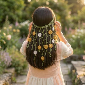 以下が含まれることがあります： 緑色のヘアバンドと、黄色と白の花が連なった手作りのヘアアクセサリー。 ボヘミアン風のデザインで、特別な日や普段使いにも適しています。 手編みで作られた、繊細で可愛らしいヘッドピースです。