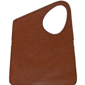 Op de afbeelding: Een bruine leren tote bag met een uniek asymmetrisch ontwerp. De tas heeft een grote, open handgreep en contrasterende stikseldetails. De tas heeft een rechthoekige vorm met een afgeronde bovenkant en een grote cirkelvormige opening.