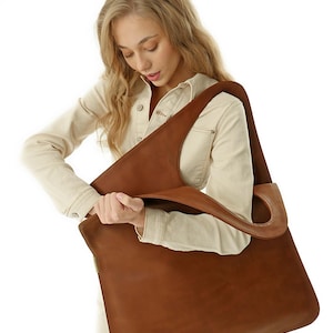 Minimalist oversized vegan leather tote with sculptural asymmetrical handle and modern architectural silhouette. This spacious extra large tote bag functions as a relaxed slouchy leather bag perfect for everyday carry. Designed as a versatile commuter bag, it easily fits a laptop as a leather macbook bag while maintaining the effortless elegance of a leather slouchy bag and the capacity of a giant leather bag.