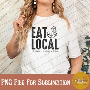 Puede incluir: Camiseta blanca con un gráfico negro que dice "Eat Local" con una imagen estilizada de una madre amamantando a un bebé. El texto debajo del gráfico dice "24 Hours / 7 Days a Week".