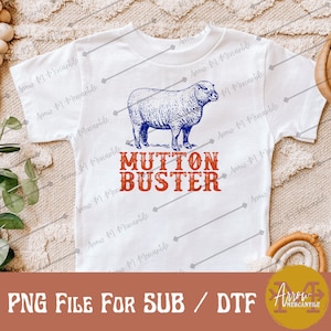 May include: White t-shirt with a blue and white illustration of a sheep and the text "MUTTON BUSTER" in red and blue.