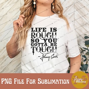 May include: White t-shirt with a black graphic that reads "Life is rough so you gotta be tough - Johnny Cash".
