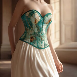 May include: A strapless teal corset with a floral pattern and a white skirt. The corset has a sweetheart neckline and is trimmed in teal. The skirt is long and flowing, creating an elegant silhouette.