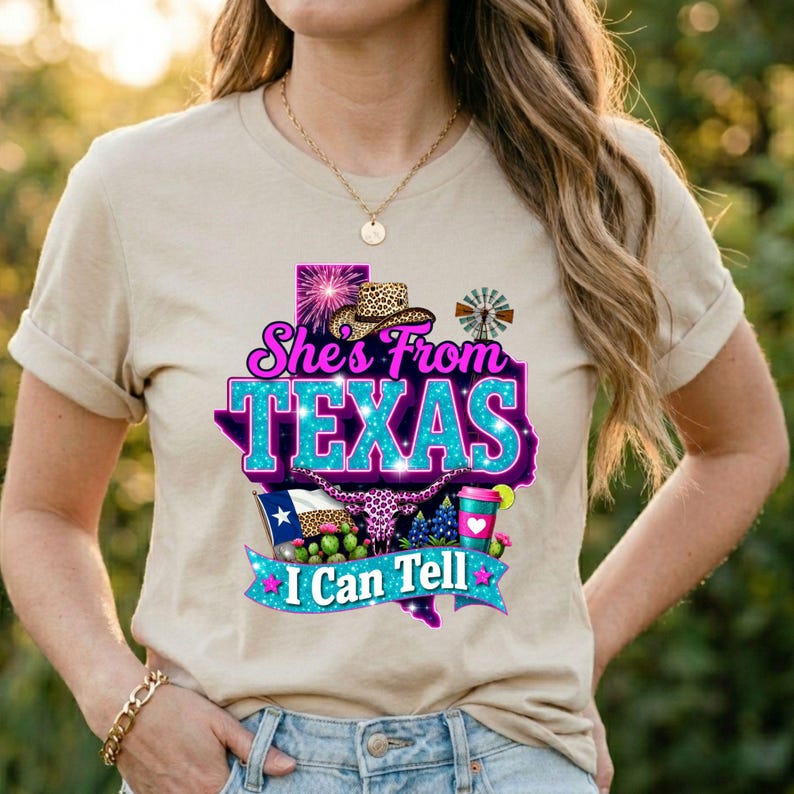 Puede incluir: Camiseta beige con un dise&ntilde;o gr&aacute;fico con el texto "She's From TEXAS I Can Tell" en un esquema de color turquesa y morado. El dise&ntilde;o incluye un mapa de Texas, un sombrero de vaquero y otros elementos tem&aacute;ticos de Texas.