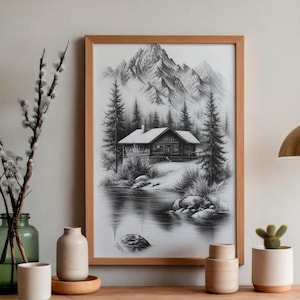 Puede incluir: Un dibujo al carboncillo en blanco y negro enmarcado que representa una cabaña de madera en un bosque con pinos altos, un lago tranquilo en primer plano y picos montañosos escarpados al fondo, en un marco de madera clara.