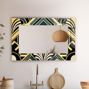 May include: Rectangular mirror with a geometric art deco design in black, gold, and teal. The mirror is hanging above a kitchen sink with a faucet, wooden cutting board, and a wooden bowl.