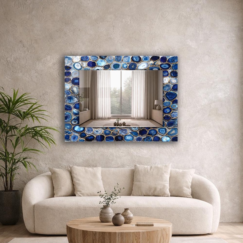Puede incluir: Espejo de pared rectangular con marco de piedras de &aacute;gata azules y blancas. El espejo refleja una habitaci&oacute;n con ventana y cortinas. El espejo est&aacute; montado en una pared de color neutro sobre un sof&aacute; crema.